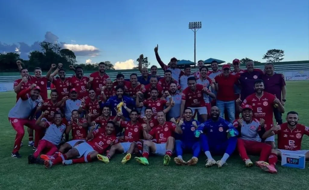 Jogadores da Anapolina celebrando uma vitória em campo de futebol, comemorando a conquista de vagas e a chance de ser campeã do interior.