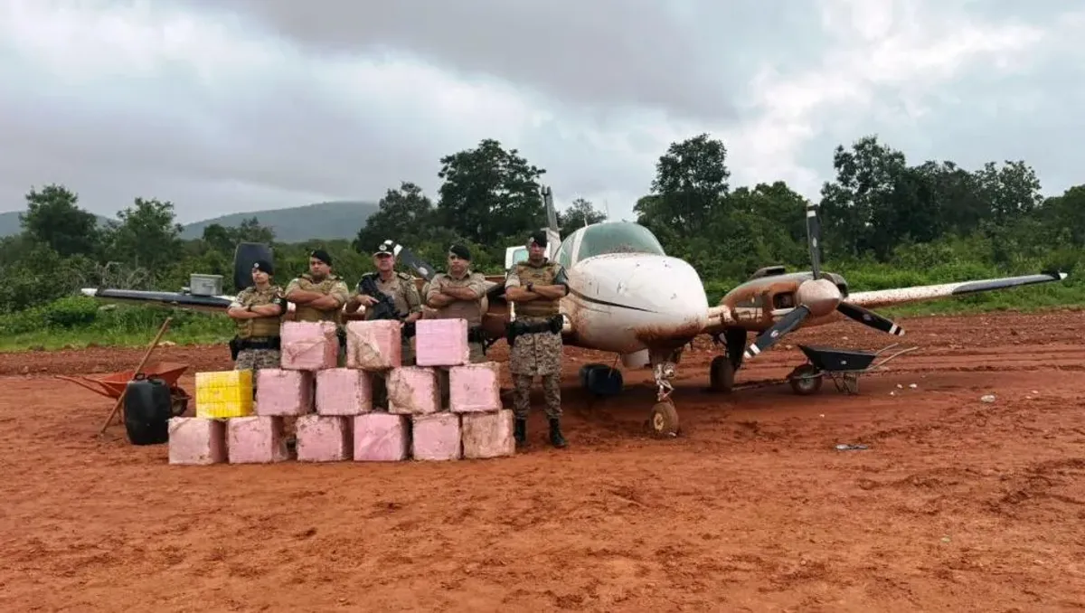 Forças de segurança inspecionam cocaína apreendida ao lado de avião em pista clandestina no Tocantins.