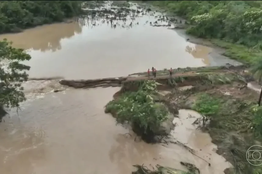 Ponte destruída pela força das chuvas no sudeste do Tocantins, com estrada alagada e vegetação arrancada, causando isolamento de famílias.