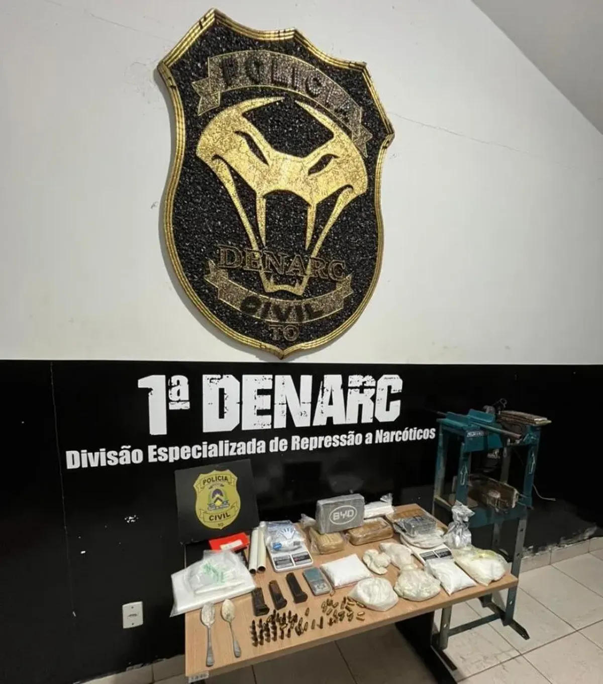 Policial civil examinando prensa hidráulica e drogas apreendidas em laboratório clandestino de cocaína em Palmas
