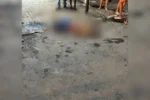 Rua central de Wanderlândia à noite, cena de crime com estabelecimento comercial ao fundo