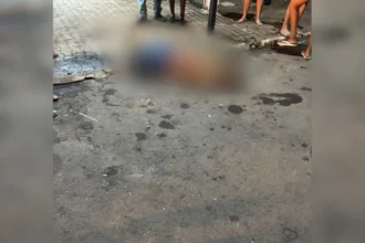 Rua central de Wanderlândia à noite, cena de crime com estabelecimento comercial ao fundo