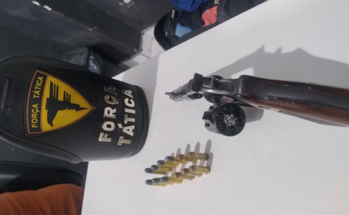 Policial militar revistando carro apreendido e policial escoltando um suspeito algemado em Porto Nacional à noite.