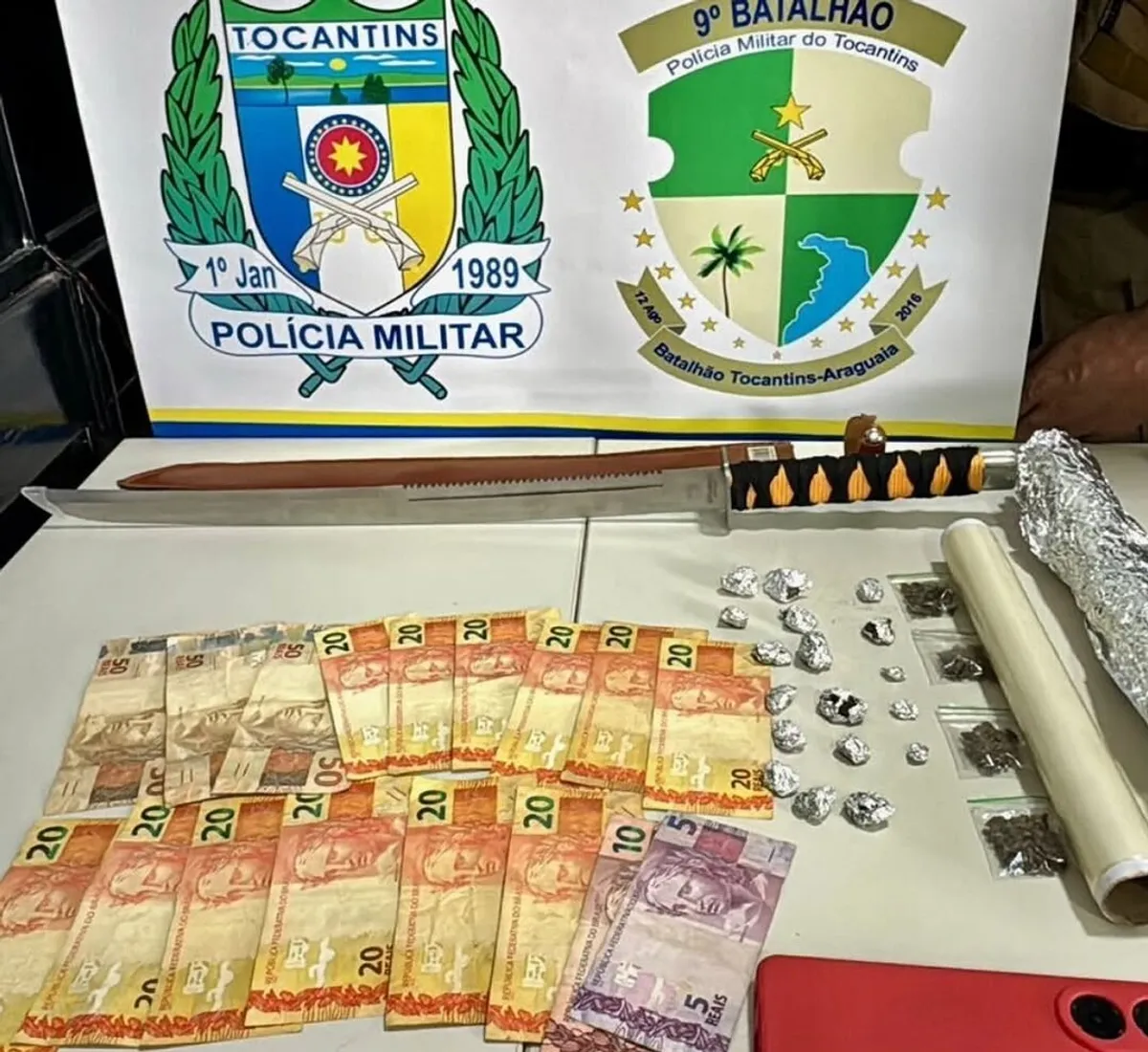 Policiais militares do Tocantins inspecionando drogas e armas apreendidas em operação em Buriti.