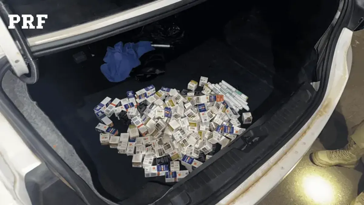 Agente da PRF inspecionando medicamentos e anabolizantes apreendidos em compartimento secreto no porta-malas de um carro na BR-153 em Guaraí.